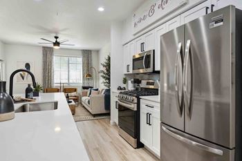 an open kitchen and living room with stainless steel appliances